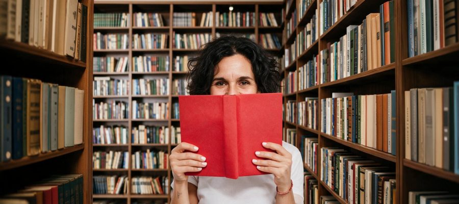 Femme derrière un livre et devant une bibliotheque